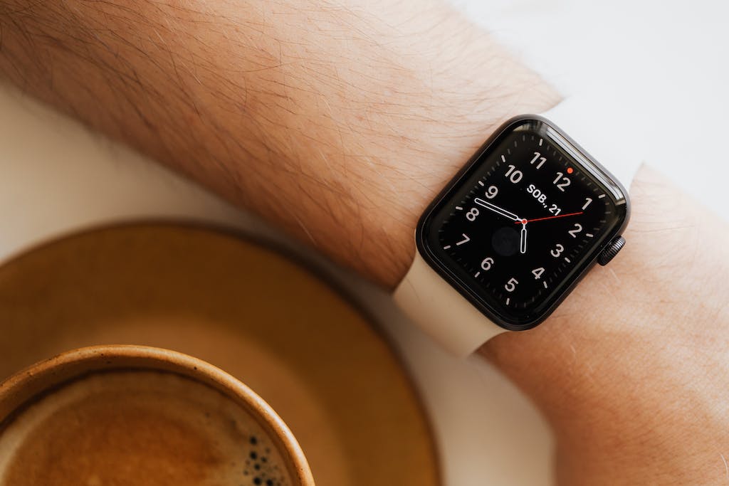 From above closeup of crop man hand with smart watch near cup of hot americano on white background