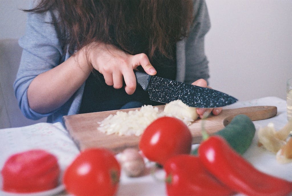 Person Cutting Vegetables on Chopping Board