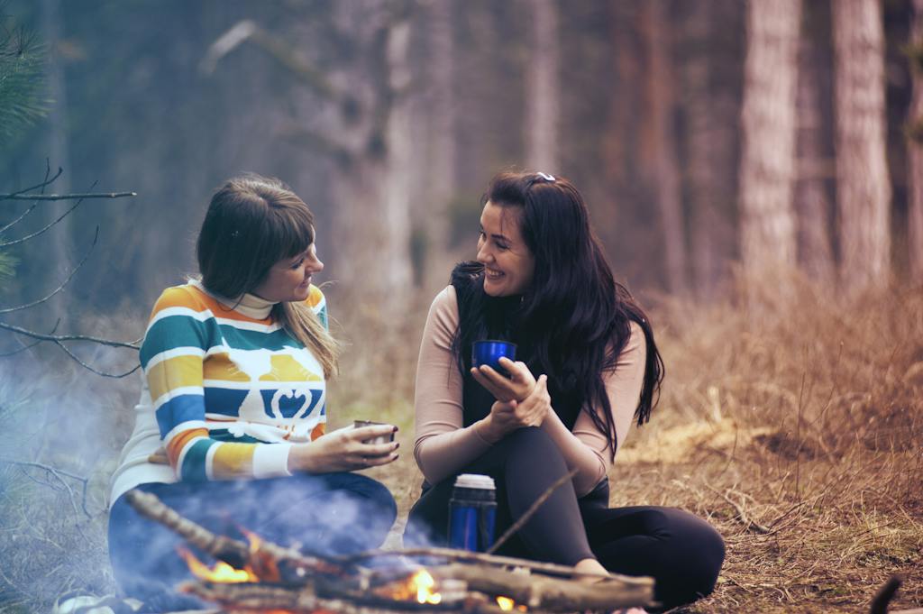 Two Women Sitting on Ground Near Bonfire - listening to build close and meaningful friendships