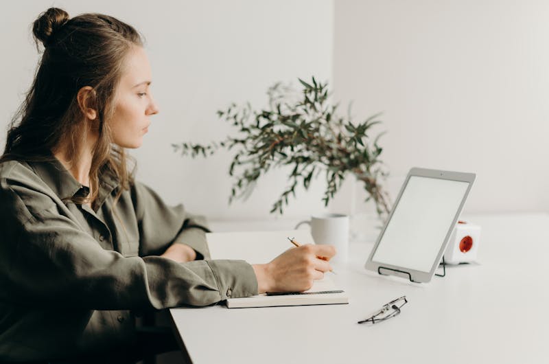 Woman in Gray Coat Using White Laptop Computer